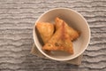 Samosas a spicy blend of vegetables or meat wrapped in a deep fried triangular pastry parcel in a white bowl Royalty Free Stock Photo