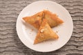 Samosas a spicy blend of vegetables or meat wrapped in a deep fried triangular pastry parcel in a white plate. Royalty Free Stock Photo