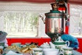 Samovar, belyashs and sweet cookies on the table in a tent installed in a birch forest. National dishes of Turkic cuisine