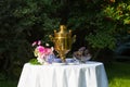 Samovar, cups of tea, pink flowers and grapes on a table covered