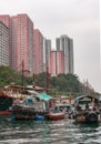 Sampans and houseboats docked in front of tall buildings in harbor of Hong Kong, China