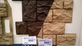Sample of basement siding with stone imitation dark brown and terracotta color in store for sale. Facade panel with price.