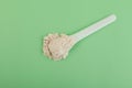 Sample of Guar gum powder in plastic spoon on light green background, top view. Food additive E412