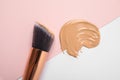 Sample of liquid foundation and makeup brush on color background Royalty Free Stock Photo