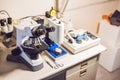 A sample preparation table in a laboratory with an optical microscope, ultrasonic cutter system and precision micrometer