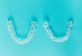 Sample of two transparent dental aligners on a sky-blue background