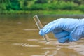 Sample water from the river for analysis. Hand in glove holding