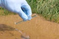 Sample water from the river for analysis. Hand in glove holding