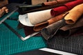 Samples of genuine leather of different colors on a craft table, surrounded by tools in a leather dressing and Royalty Free Stock Photo