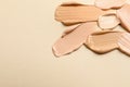 Samples of skin foundation on beige background, closeup. Space for text