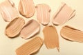 Samples of skin foundation on beige background, top view