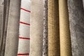 Samples of synthetic carpets of various patterns of white yellow gray color suspended on the crossbar. Textiles, Backgrounds, desi