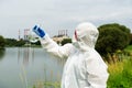 Sampling from open water. A scientist or biologist takes a water sample near an industrial plant. A sample of water in a Royalty Free Stock Photo