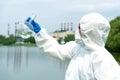 Sampling from open water. A scientist or biologist takes a water sample near an industrial plant. A sample of water in a