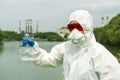 Sampling from open water. A scientist or biologist takes a water sample near an industrial plant. A sample of water in a Royalty Free Stock Photo