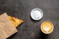 Samsa in paper envelope and cappuccino in paper cup on gray background top view