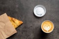 Samsa in paper envelope and cappuccino in paper cup on gray background top view