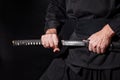 The samurai holding a Japanese katana sword. Photo of a warrior dressed in black clothes in low key Royalty Free Stock Photo