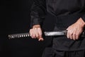 The samurai holding a Japanese katana sword. Photo of a warrior dressed in black clothes in low key with selective Royalty Free Stock Photo