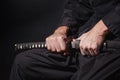 The samurai holding a Japanese katana sword. Photo of a warrior dressed in black clothes in low key with selective Royalty Free Stock Photo