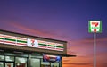 Illuminated lighting of the 7-Eleven convenience store and logo sign pole on street at sunset time