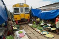 Train passes by the Mae Klong railway tracks market in Samut Songkram, Thailand.