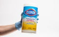 SAN ANTONIO, TEXAS - 04/29/2020 - Woman hand wearing surgical protective glove holds plastic dispenser of Clorox bleach wipes agai