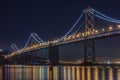 San Francisco Bay Bridge at night, lit up by yellow and blue lights, reflecting of the water in the Bay, long exposure Royalty Free Stock Photo