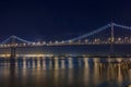 San Francisco Bay Bridge at night, lit up by yellow and blue lights, reflecting of the water in the Bay, long exposure Royalty Free Stock Photo