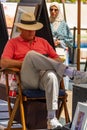 San Francisco, California, USA - July 05, 2019, a painting dealer sits on a chair reading a book at Union Square in the city of