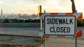 Sidewalk closed sign with view of San Francisco port at sunset