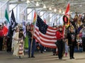 Native Americans in traditional outfits carry traditional eagle staff and flags at powwow Grand Entry in San Francisco