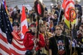 Native Americans in traditional outfits carry traditional eagle staff and flags at powwow Grand Entry in San Francisco