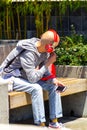 San Francisco, USA - July 12, 2019, a young stylish bald man sits on a bench in the street in bright red headphones and