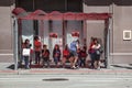 people wait in a booth at a busstop for the next bus in midday heat