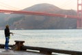 SAN FRANCISCO, USA - OCTOBER 12, 2018: A man fishing at sunrise with the Golden Gate Bridge in the background