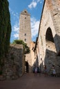 SAN GIMIGNANO, ITALY - AUGUST 18th 2018: Tourists shoot walls of San Gimignano, in Tuscany, staying in the shade during a very hot