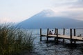 Three tourists sitting on the pier for watching sunset with volcano San Pedro in the background Royalty Free Stock Photo