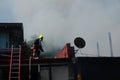 Lone fireman on top of the roof walking away from thick smoke from burning house