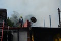 Lone fireman on top of the roof walking away from thick smoke from burning house