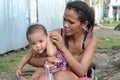 Woman beggar with boils cuddling daughter at church yard