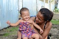 Woman beggar with boils cuddling daughter at church yard