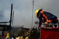 Woman Fire Fighter With Protective Hat crawling on top of fire truck in the area of burning house