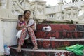 Mother cuddling baby son at church yard patio selling candles