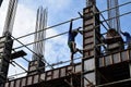 Filipino construction steel-man climbing down using scaffolding pipes on high-rise building