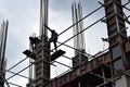 Filipino construction steel-men working joining column steel pieces on board scaffolding pipes on high-rise building