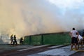 Firemen and volunteers on rooftop put out fire using fire hose during house fire that gutted interior shanty houses