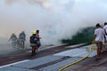 Firemen and volunteers on rooftop put out fire using fire hose during house fire that gutted interior shanty houses