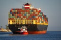 A tugboat steers a fully loaded container ship through the Port of Los Angeles.