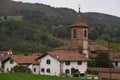 San Pedro church in Erratzu, surrounded by white houses with red roofs and green hills in the back Royalty Free Stock Photo